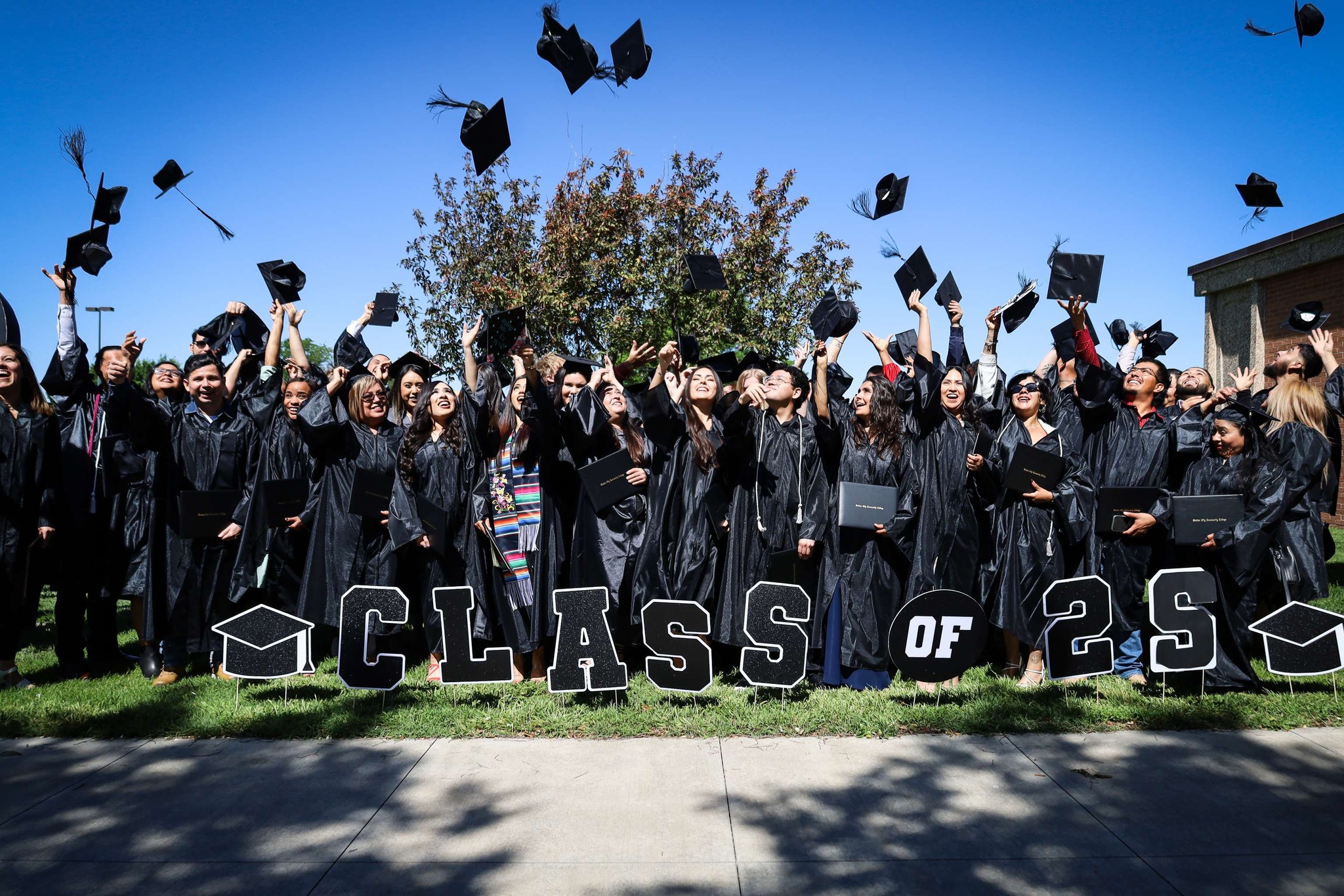 Group of GCCCA students celebrating graduation by throwing caps in the air