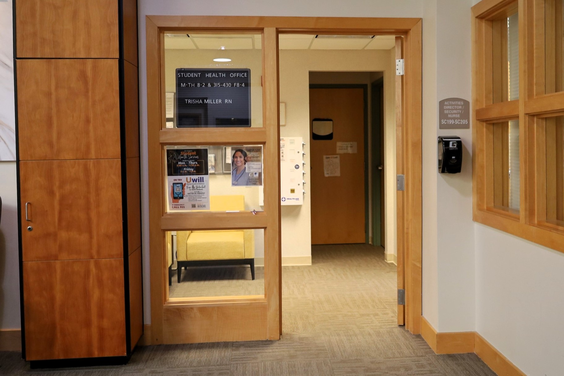 Student health office entrance with glass door, signage, and hallway interior.